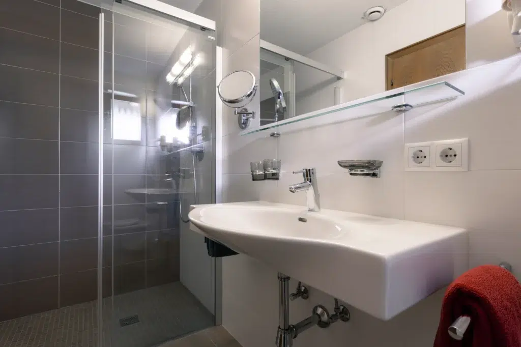 Elegantes Badezimmer mit Glasdusche, großem Waschbecken und modernen Armaturen.